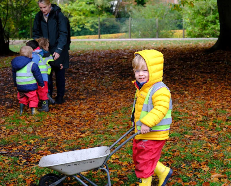 child playing with wheel barrow outside